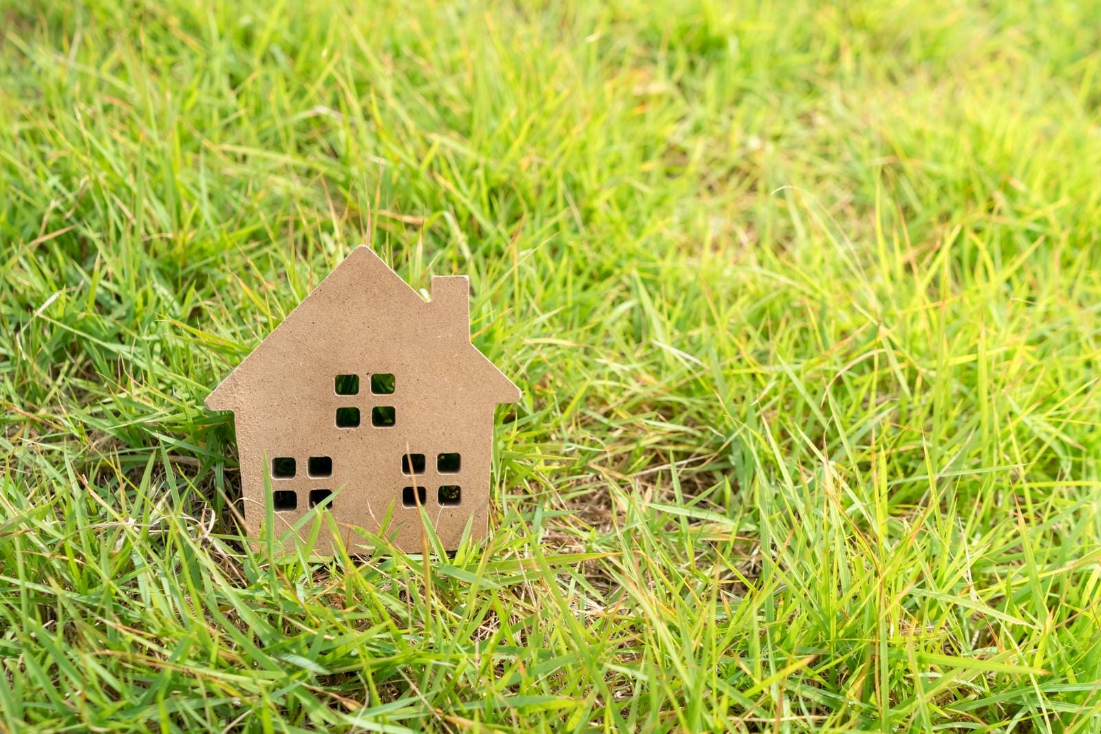 Closed up tiny home model on green grass with sunlight.